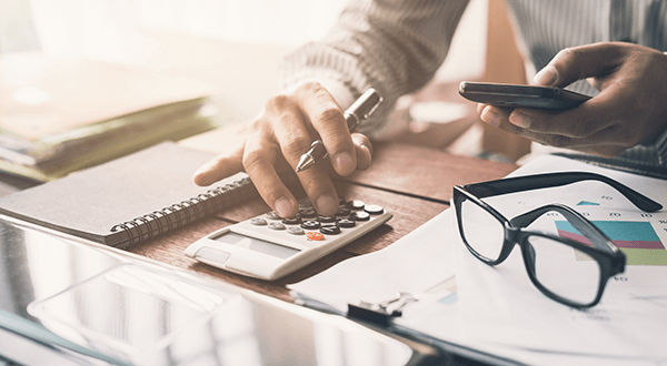 A person using a calculator at a desk stock photo